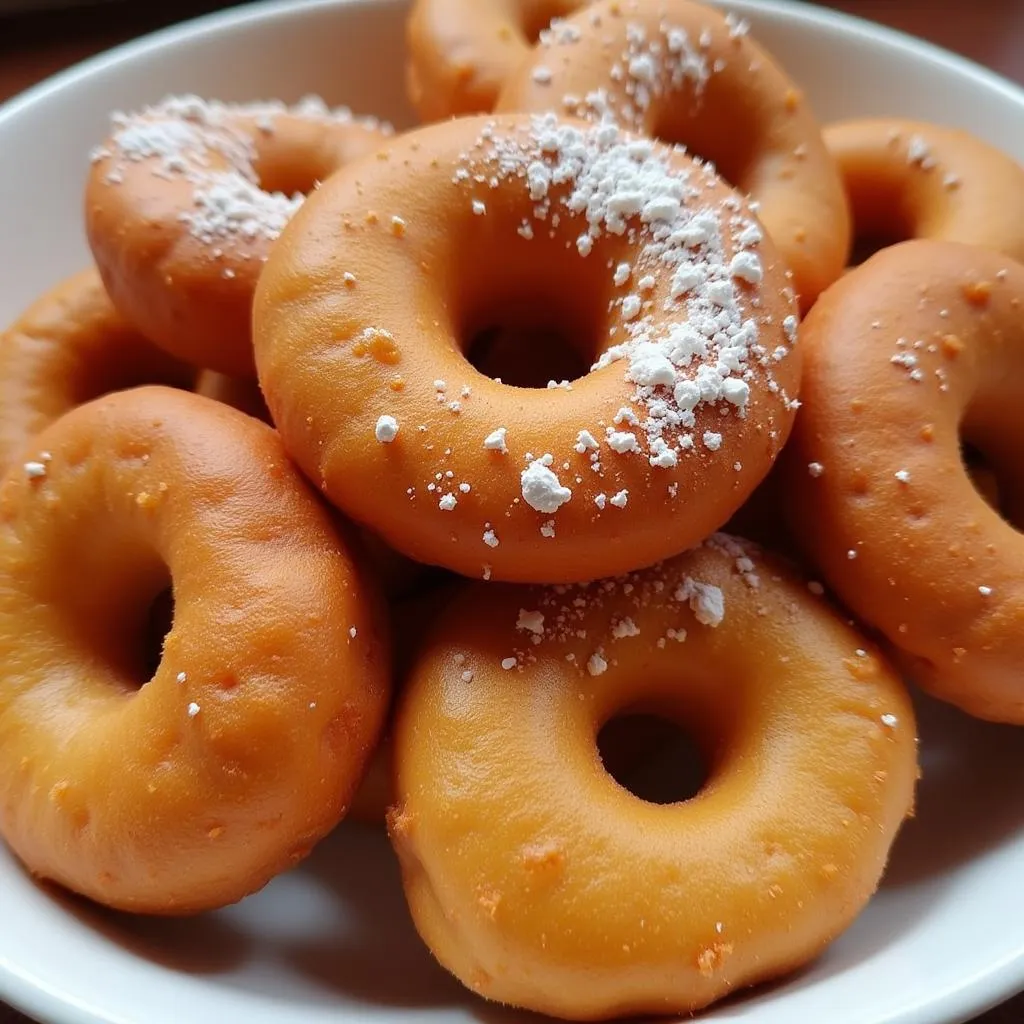 A plate of mandazi, African doughnuts, dusted with powdered sugar